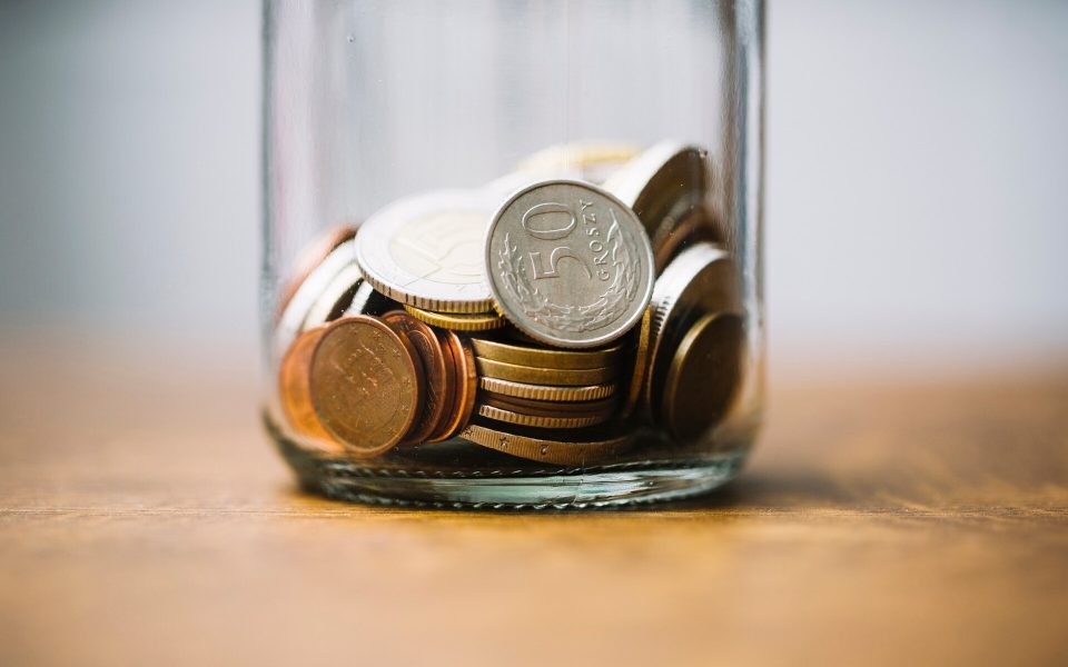 Svenska och utländska mynt samlade i en glasburk på ett bord