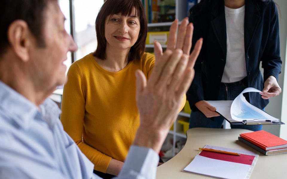 Vuxna deltagare samtalar engagerat vid ett bord med papper under en kurs