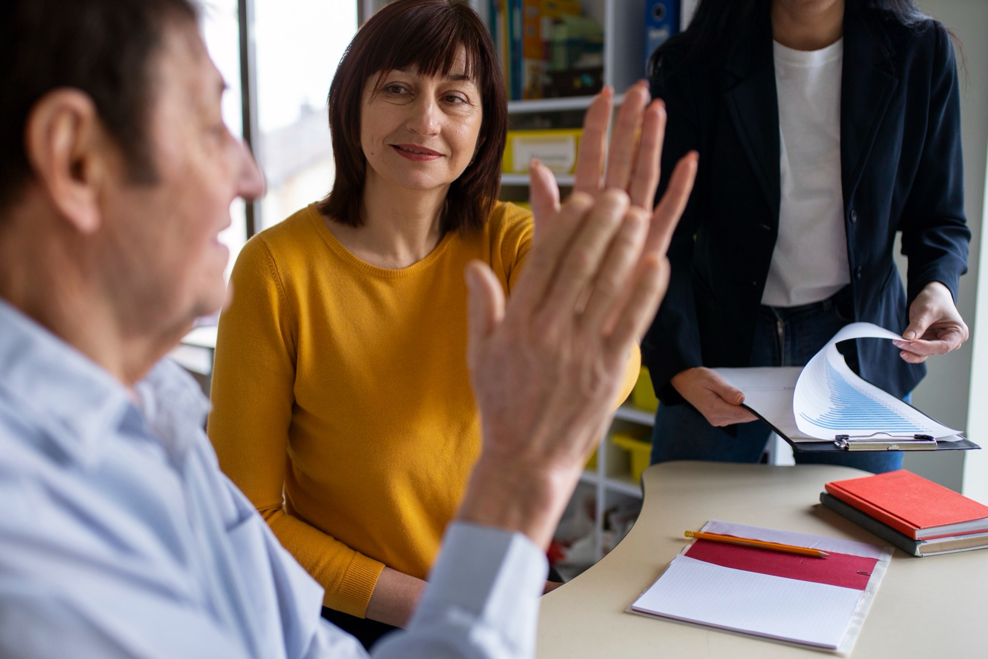 Vuxna deltagare samtalar engagerat vid ett bord med papper under en kurs